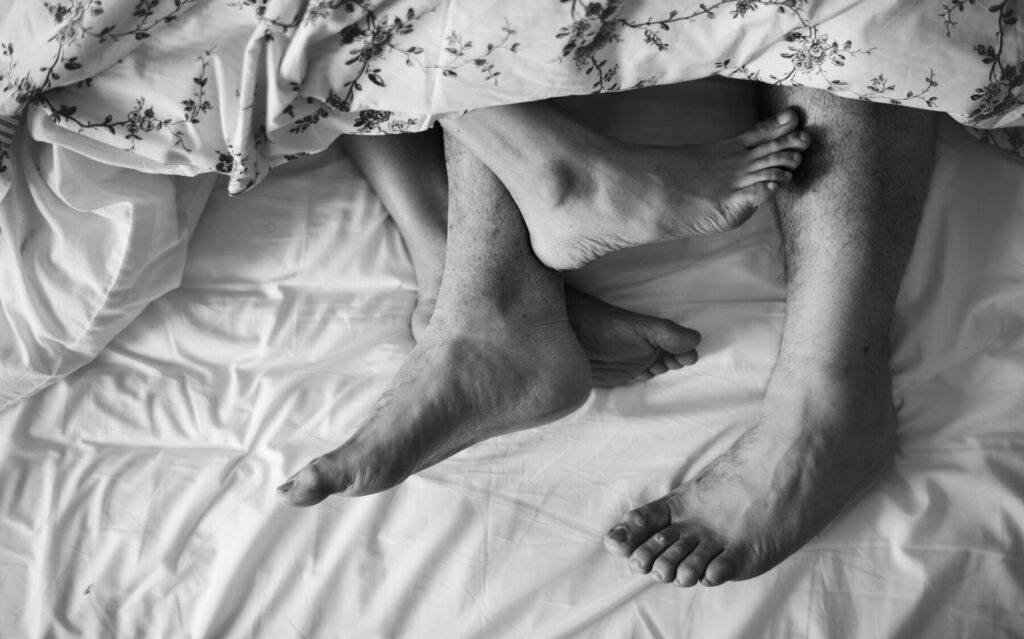Couple in bed, representing the struggles of sex addiction and the impact on relationships and personal well-being.