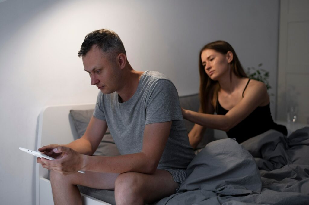 Couple in bed experiencing the emotional distance caused by porn addiction and its impact on relationships.